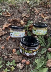 Tri tegle Kranci domaćih kremova (Beli lešnik, Crni krem, Pistać) poređane na zemlji u zasadu Lešnikovca u Divcima, okružene celim plodovima lešnika u ljusci i suvim jesenjim lišćem.